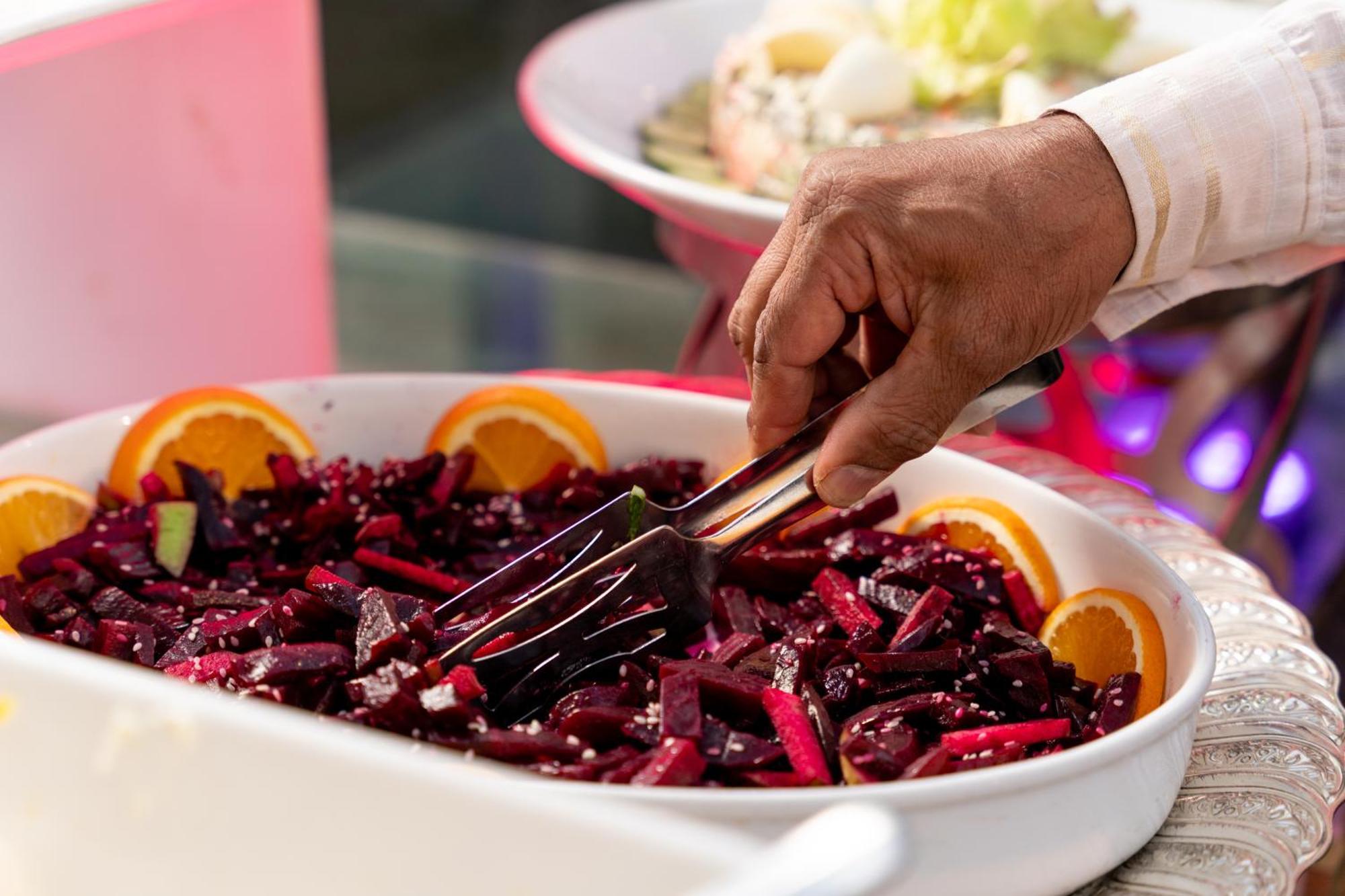 쉐라톤 담맘 호텔 앤 컨벤션 센터 외부 사진 A hand using a buffet server to serve food
